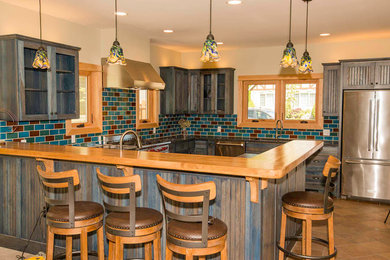 Inspiration for a large rustic u-shaped brown floor kitchen remodel in Portland with a double-bowl sink, shaker cabinets, blue cabinets, granite countertops, blue backsplash, subway tile backsplash, stainless steel appliances and a peninsula
