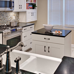 Design ideas for a small traditional u-shaped eat-in kitchen in Atlanta with stainless steel appliances, soapstone benchtops, recessed-panel cabinets, white cabinets, a farmhouse sink, multi-coloured splashback, glass tile splashback, porcelain floors, with island, beige floor and green benchtop.