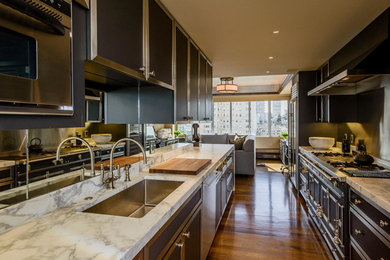 Photo of a large contemporary galley kitchen/diner in San Francisco with a submerged sink, raised-panel cabinets, black cabinets, marble worktops, white splashback, stone slab splashback, stainless steel appliances, medium hardwood flooring and no island.