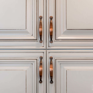 Photo of a mid-sized galley eat-in kitchen in New York with an undermount sink, raised-panel cabinets, yellow cabinets, granite benchtops, grey splashback, cement tile splashback, stainless steel appliances, plywood floors, a peninsula and beige floor.