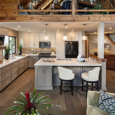 Inspiration for a mid-sized contemporary l-shaped dark wood floor and brown floor open concept kitchen remodel in San Luis Obispo with a single-bowl sink, recessed-panel cabinets, gray cabinets, quartz countertops, beige backsplash, ceramic backsplash, black appliances, an island and white countertops