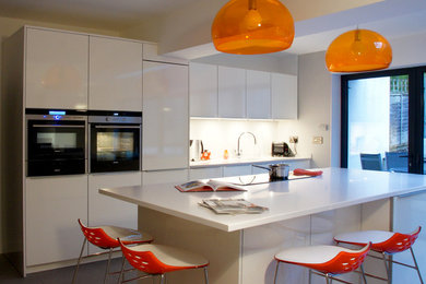 Photo of a medium sized contemporary kitchen/diner in Other with a submerged sink, flat-panel cabinets, white cabinets, composite countertops, black appliances, ceramic flooring and an island.