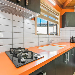 This is an example of a small modern single-wall separate kitchen in Sunshine Coast with an integrated sink, solid surface benchtops, yellow splashback, subway tile splashback and orange benchtop.