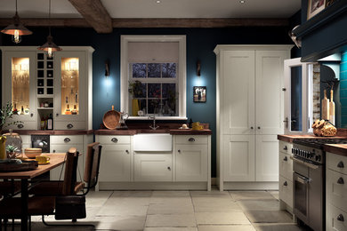 Example of a large classic l-shaped concrete floor and gray floor eat-in kitchen design in Other with a farmhouse sink, shaker cabinets, white cabinets, wood countertops and no island