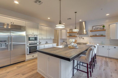 フェニックスにある高級な広いコンテンポラリースタイルのおしゃれなキッチン (エプロンフロントシンク、白いキャビネット、シルバーの調理設備) の写真