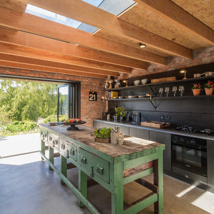 Idee per una cucina country di medie dimensioni con ante nere, paraspruzzi nero, elettrodomestici neri, pavimento in cemento, isola e nessun'anta
