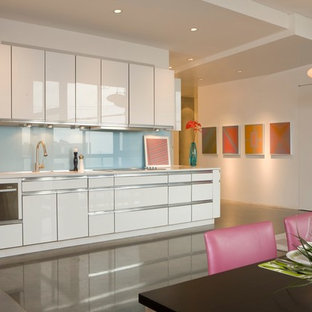 Foto di una cucina lineare minimalista con elettrodomestici in acciaio inossidabile, ante lisce, ante bianche, paraspruzzi blu e paraspruzzi con lastra di vetro