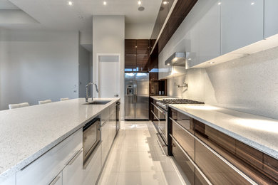 Large minimalist l-shaped ceramic tile kitchen photo in Montreal with an undermount sink, flat-panel cabinets, dark wood cabinets, quartzite countertops, white backsplash, stone slab backsplash, stainless steel appliances and an island