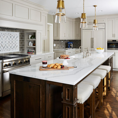 Kitchen - traditional l-shaped dark wood floor and brown floor kitchen idea in Minneapolis with a farmhouse sink, recessed-panel cabinets, gray cabinets, gray backsplash, subway tile backsplash, stainless steel appliances, an island and white countertops