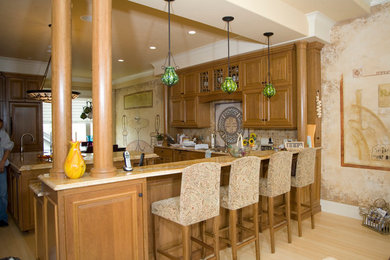 Eat-in kitchen - large traditional u-shaped light wood floor and brown floor eat-in kitchen idea in Minneapolis with raised-panel cabinets, medium tone wood cabinets, granite countertops, brown backsplash, stone tile backsplash, paneled appliances and an island