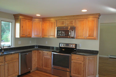 Example of a large classic u-shaped light wood floor eat-in kitchen design in Boston with a single-bowl sink, raised-panel cabinets, light wood cabinets, granite countertops, stainless steel appliances and no island