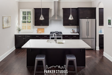 Inspiration for a mid-sized timeless u-shaped dark wood floor eat-in kitchen remodel in Atlanta with an undermount sink, recessed-panel cabinets, black cabinets, granite countertops, white backsplash, porcelain backsplash, stainless steel appliances and an island