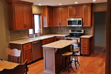Mid-sized transitional l-shaped light wood floor eat-in kitchen photo in Minneapolis with an undermount sink, shaker cabinets, medium tone wood cabinets, quartz countertops, gray backsplash, subway tile backsplash, stainless steel appliances and an island