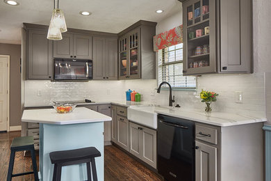 Small cottage chic l-shaped medium tone wood floor and brown floor eat-in kitchen photo in Dallas with a farmhouse sink, shaker cabinets, gray cabinets, quartz countertops, white backsplash, ceramic backsplash, black appliances, an island and white countertops