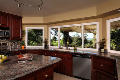 Large transitional u-shaped eat-in kitchen photo in Orange County with an undermount sink, raised-panel cabinets, dark wood cabinets, granite countertops, multicolored backsplash, matchstick tile backsplash, stainless steel appliances and an island