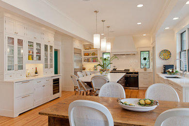 Large transitional u-shaped light wood floor open concept kitchen photo in Other with an undermount sink, shaker cabinets, white backsplash, an island, white cabinets, quartzite countertops, subway tile backsplash and stainless steel appliances
