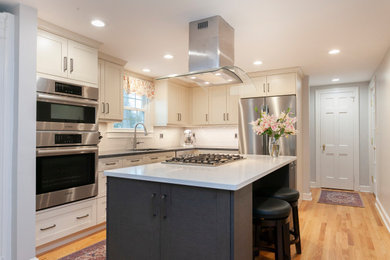 Example of a mid-sized transitional l-shaped medium tone wood floor and yellow floor eat-in kitchen design in Bridgeport with a single-bowl sink, recessed-panel cabinets, white cabinets, quartz countertops, white backsplash, ceramic backsplash, stainless steel appliances, an island and white countertops