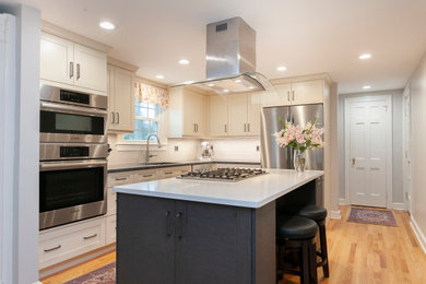 This is an example of a medium sized classic l-shaped kitchen/diner in Bridgeport with a single-bowl sink, recessed-panel cabinets, white cabinets, engineered stone countertops, white splashback, ceramic splashback, stainless steel appliances, medium hardwood flooring, an island, yellow floors and white worktops.