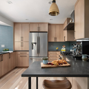Inspiration for a contemporary u-shaped separate kitchen in Denver with an undermount sink, light wood cabinets, quartz benchtops, blue splashback, glass tile splashback, stainless steel appliances, light hardwood floors and black benchtop.