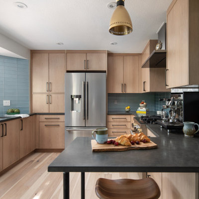 Trendy u-shaped light wood floor enclosed kitchen photo in Denver with an undermount sink, light wood cabinets, quartz countertops, blue backsplash, glass tile backsplash, stainless steel appliances and black countertops
