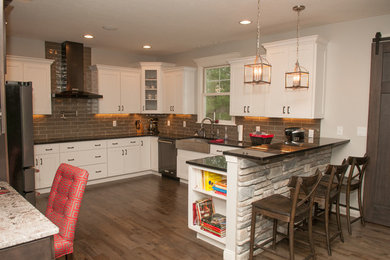Large transitional u-shaped medium tone wood floor and brown floor eat-in kitchen photo in Other with a farmhouse sink, shaker cabinets, white cabinets, gray backsplash, stainless steel appliances, a peninsula, quartzite countertops and subway tile backsplash