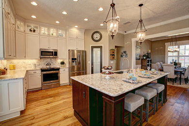 Example of a medium tone wood floor kitchen design in Tampa with a single-bowl sink, shaker cabinets, white cabinets, quartzite countertops, stainless steel appliances and an island