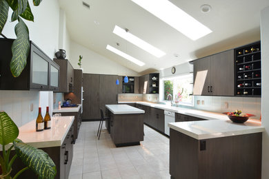 Enclosed kitchen - large modern u-shaped white floor and ceramic tile enclosed kitchen idea in San Luis Obispo with an undermount sink, flat-panel cabinets, brown cabinets, quartz countertops, white backsplash, glass tile backsplash, paneled appliances, white countertops and an island
