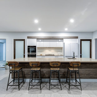 Design ideas for a contemporary galley open plan kitchen in Sunshine Coast with an undermount sink, flat-panel cabinets, white cabinets, beige splashback, white appliances, with island, grey floor, beige benchtop, quartz benchtops, porcelain splashback and porcelain floors.