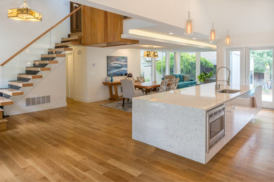 Inspiration for a medium sized modern open plan kitchen in New York with a submerged sink, stainless steel appliances, light hardwood flooring and an island.