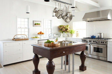 Klassische Küche in L-Form mit weißen Schränken, Marmor-Arbeitsplatte, Küchenrückwand in Weiß, Küchengeräten aus Edelstahl, Kücheninsel, Waschbecken, Rückwand aus Metrofliesen und hellem Holzboden in Boston