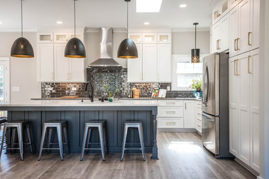 Eat-in kitchen - large modern l-shaped light wood floor and beige floor eat-in kitchen idea in Atlanta with a drop-in sink, recessed-panel cabinets, white cabinets, black backsplash, porcelain backsplash, stainless steel appliances, an island and white countertops