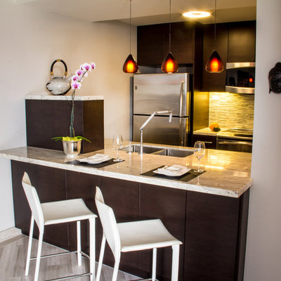 Example of a small trendy galley medium tone wood floor and brown floor open concept kitchen design in Hawaii with an undermount sink, flat-panel cabinets, dark wood cabinets, granite countertops, green backsplash, glass tile backsplash, stainless steel appliances and a peninsula
