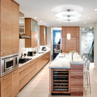 Large contemporary galley kitchen/diner in Chicago with flat-panel cabinets, light wood cabinets, white splashback, metro tiled splashback, integrated appliances, an island, a submerged sink, composite countertops and ceramic flooring.