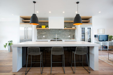 Inspiration for a contemporary galley light wood floor and beige floor open concept kitchen remodel in New York with stainless steel cabinets, gray backsplash, stone slab backsplash, stainless steel appliances and an island