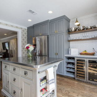Traditional kitchen designs - Example of a classic l-shaped medium tone wood floor and brown floor kitchen design in Houston with raised-panel cabinets, gray cabinets, white backsplash, subway tile backsplash, stainless steel appliances, an island and white countertops
