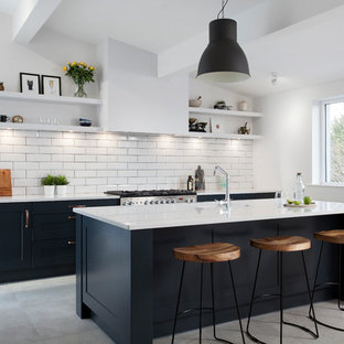 Classic galley kitchen in Belfast with a single-bowl sink, stainless steel appliances, an island, shaker cabinets, blue cabinets, white splashback, metro tiled splashback, grey floors and white worktops.