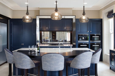 ベルファストにあるラグジュアリーな巨大なトランジショナルスタイルのおしゃれなキッチン (一体型シンク、落し込みパネル扉のキャビネット、青いキャビネット、珪岩カウンター、メタリックのキッチンパネル、ミラータイルのキッチンパネル、黒い調理設備、セラミックタイルの床) の写真
