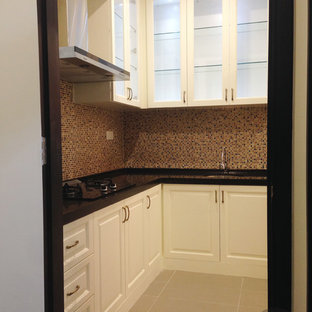 Small traditional l-shaped separate kitchen in Other with an undermount sink, beaded inset cabinets, beige cabinets, solid surface benchtops, brown splashback, mosaic tile splashback, black appliances and porcelain floors.