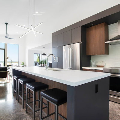 Large minimalist concrete floor and brown floor open concept kitchen photo in Grand Rapids with an undermount sink, flat-panel cabinets, dark wood cabinets, quartz countertops, white backsplash, stainless steel appliances, an island and white countertops