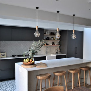 Inspiration for a contemporary eat-in kitchen in London with a farmhouse sink, flat-panel cabinets, grey cabinets, quartzite benchtops, white splashback, subway tile splashback, ceramic floors, multi-coloured floor, stainless steel appliances, with island and white benchtop.