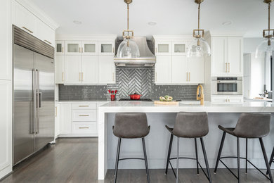 Kitchen - transitional l-shaped dark wood floor and brown floor kitchen idea in DC Metro with shaker cabinets, white cabinets, gray backsplash, stainless steel appliances, an island, white countertops and subway tile backsplash