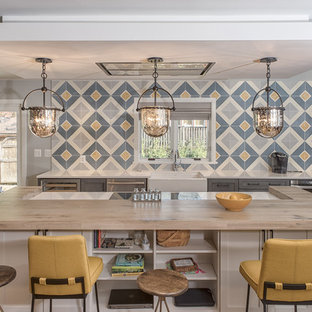 Modelo de cocina de estilo de casa de campo con fregadero sobremueble, armarios estilo shaker, puertas de armario grises, encimera de madera, salpicadero azul, salpicadero de azulejos de cerámica, suelo de madera clara y una isla