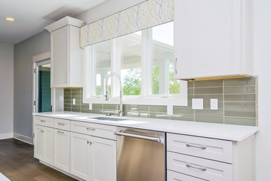 シャーロットにある広いモダンスタイルのおしゃれなキッチン (ドロップインシンク、フラットパネル扉のキャビネット、白いキャビネット、クオーツストーンカウンター、緑のキッチンパネル、ガラスタイルのキッチンパネル、シルバーの調理設備、無垢フローリング) の写真