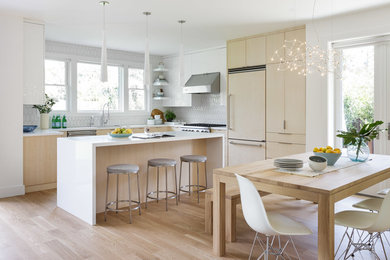 Design ideas for a medium sized contemporary l-shaped open plan kitchen in Sacramento with flat-panel cabinets, light wood cabinets, white splashback, integrated appliances, light hardwood flooring, an island, beige floors, a built-in sink and ceramic splashback.