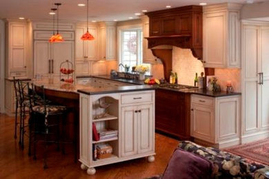 Example of a large classic l-shaped medium tone wood floor open concept kitchen design in Philadelphia with a single-bowl sink, beaded inset cabinets, granite countertops, stone tile backsplash, paneled appliances, an island, beige backsplash and black countertops