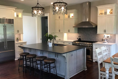 Large farmhouse l-shaped dark wood floor and brown floor eat-in kitchen photo in Other with an undermount sink, flat-panel cabinets, beige cabinets, quartz countertops, gray backsplash, glass tile backsplash, stainless steel appliances, an island and beige countertops