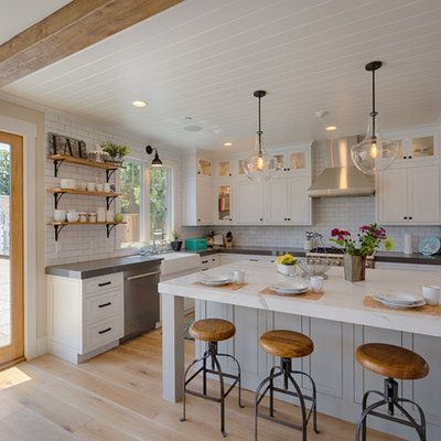 Inspiration for a large country l-shaped medium tone wood floor and brown floor enclosed kitchen remodel in San Francisco with a farmhouse sink, shaker cabinets, white cabinets, white backsplash, subway tile backsplash, stainless steel appliances, an island and quartzite countertops