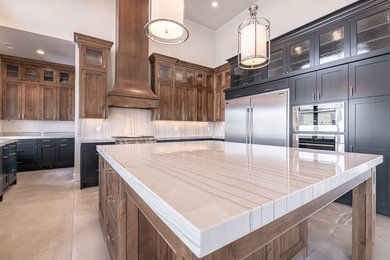 Large farmhouse u-shaped concrete floor and gray floor open concept kitchen photo in Salt Lake City with an undermount sink, glass-front cabinets, black cabinets, quartzite countertops, beige backsplash, stone slab backsplash, stainless steel appliances, an island and beige countertops