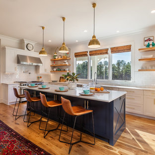 Imagen de cocina comedor en U, de estilo de casa de campo, grande, con fregadero sobremueble, salpicadero blanco, salpicadero de azulejos de cerámica, electrodomésticos de acero inoxidable, suelo de madera en tonos medios, una isla, suelo marrón, encimeras blancas, armarios estilo shaker, puertas de armario azules y encimera de cuarzo compacto