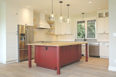 Example of a mid-sized cottage u-shaped light wood floor and brown floor eat-in kitchen design in Other with a farmhouse sink, shaker cabinets, red cabinets, wood countertops, white backsplash, stainless steel appliances and an island